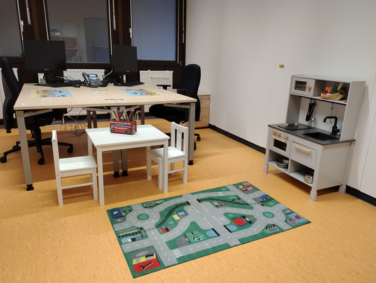 Bild des Familienbüros mit einem Tisch, mehreren Sitzmöglichkeiten und Spielzeug für Kindern