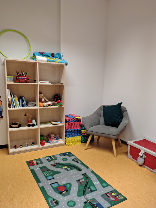 Eine Spielecke im Familienbüro mit einem Schrank mit viel Kinderspielzeug und einem Stuhl