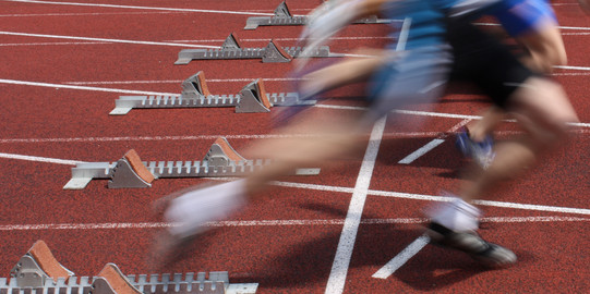Mehrere Sprinter nebeneinander starten aus Startblöcken.