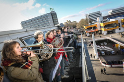 Eine Gruppe Blasmusikerinnen und -musiker steht auf dem Dach der Bibliothek und gibt ein Konzert.