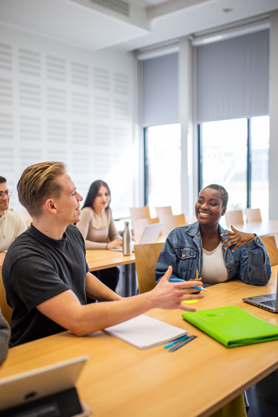 Studierende unterhalten sich im Seminarraum