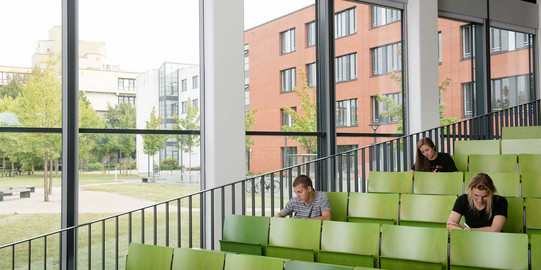 Drei Studierende sitzen im Hörsaal.
