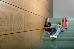 Zwei Studentinnen sitzen mit Laptop und TU-Logo auf einer Treppe.