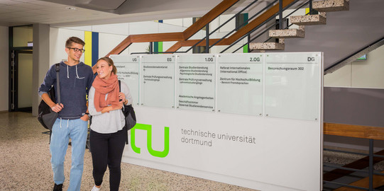 Zwei Studierende laufen durch ein Foyer.