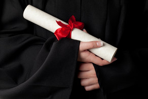 Urkunde Ein gerolltes Dokument mit roter Schleife wird von Händen gehalten.