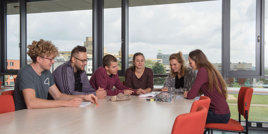 Studierende sitzen mit Lernunterlagen am Tisch.