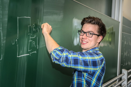 Ein Student schreibt eine mathematische Gleichung an eine Tafel